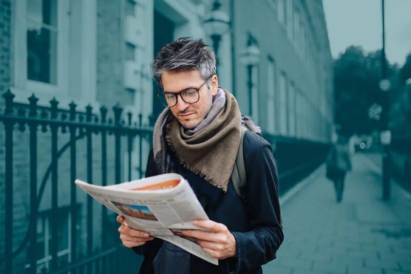 Hombre leyendo prensa, soluciones de correo y publicaciones Asendia.