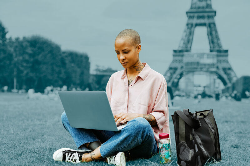  Mujer usando laptop cerca de la Torre Eiffel, gestionando envíos con Asendia