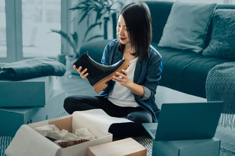 Mujer desempaquetando zapatos, soluciones e-PAQ de Asendia para comercio electrónico.