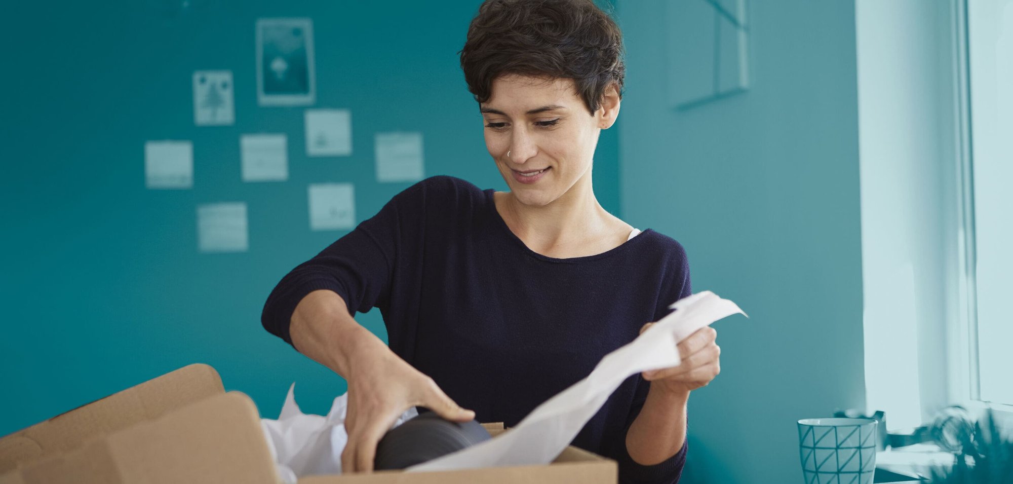 Mujer revisando paquete para envío postal internacional con e-PAQ Plus de Asendia