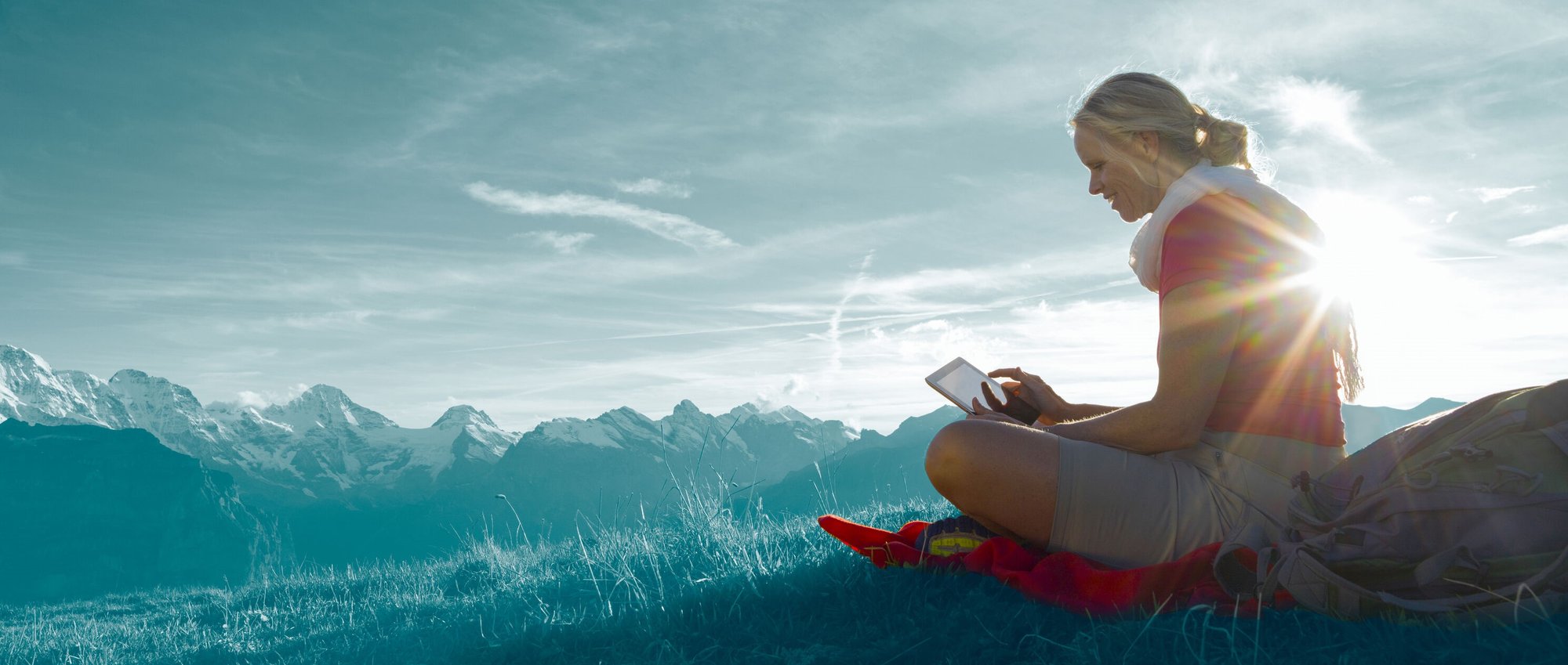 Mujer revisando envío postal con tablet en montaña